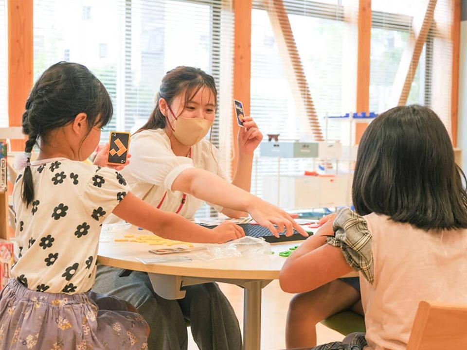 A woman is playing a card game with two children