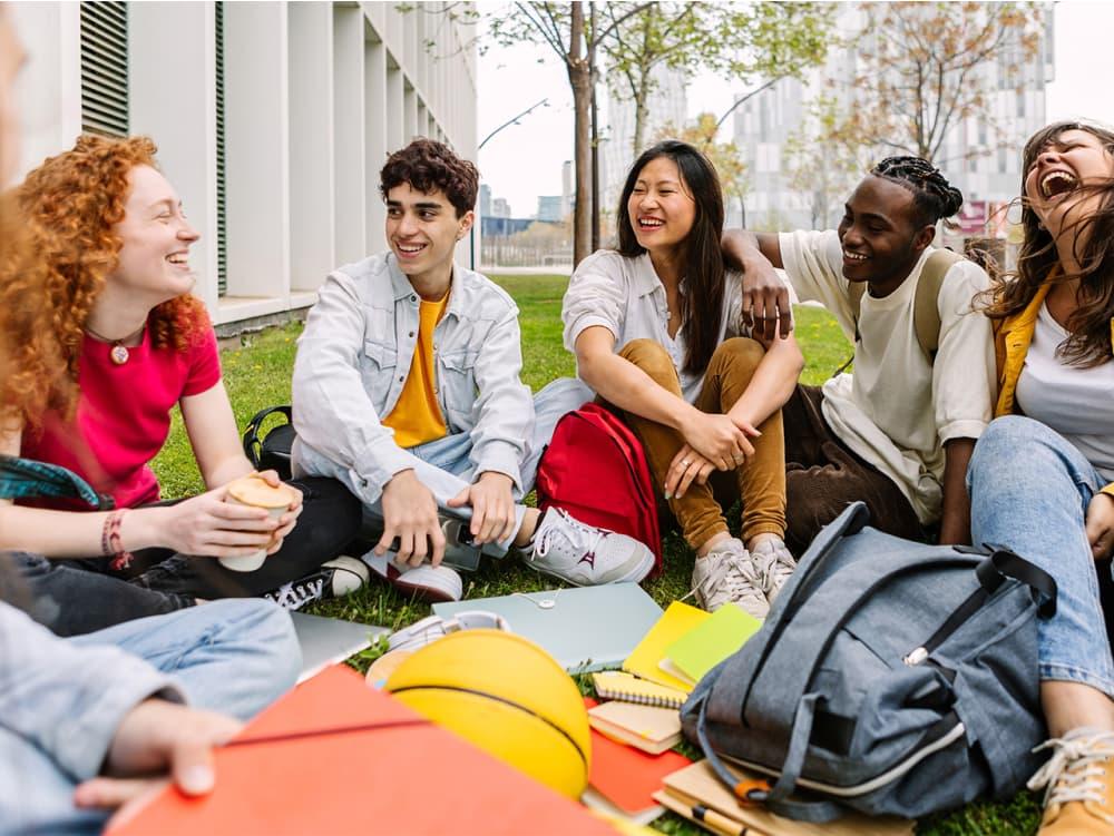 Five foreign students are smiling and conversing.